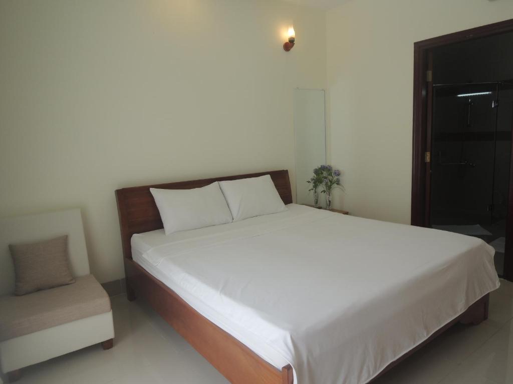une chambre avec un grand lit et une chaise dans l'établissement Mango Tree, à Vung Tau