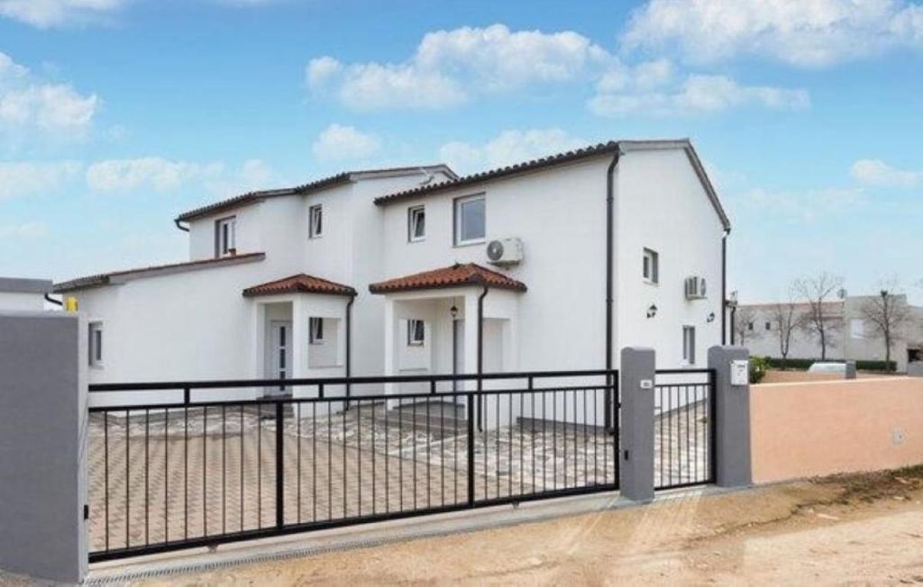 a white building with a fence in front of it at Apartman mirna lokacija s pogledom i parkingom in Vodnjan