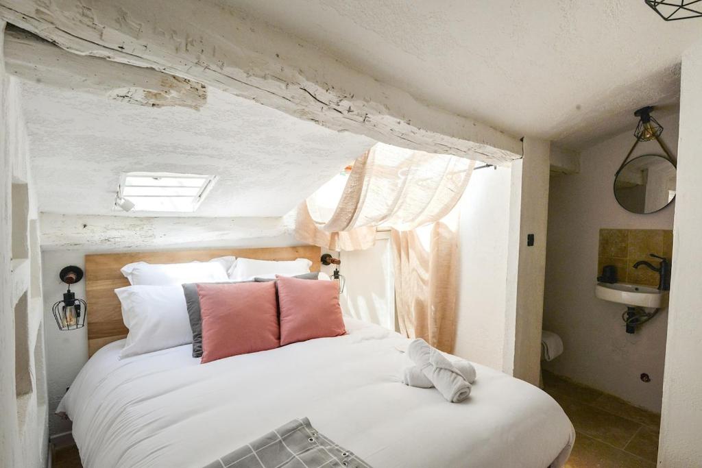 una camera da letto con un grande letto bianco con cuscini rosa di Flat village Saint-Paul-de-Vence 4P a Saint-Paul-de-Vence