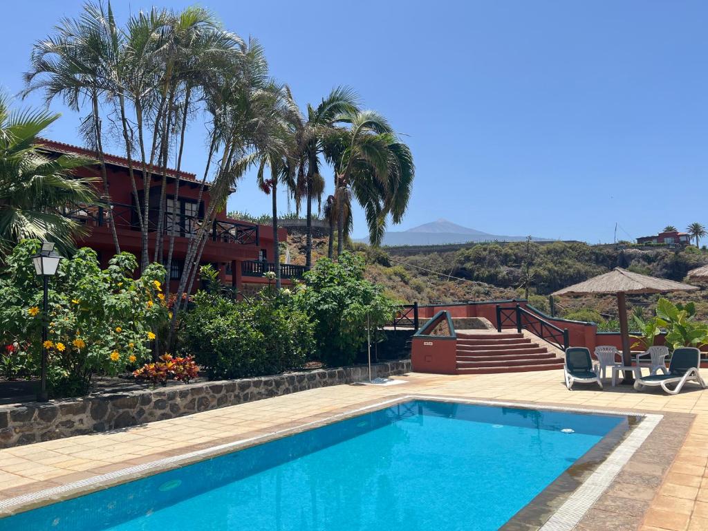 a swimming pool in front of a house with palm trees at Finca La Romera in La Orotava