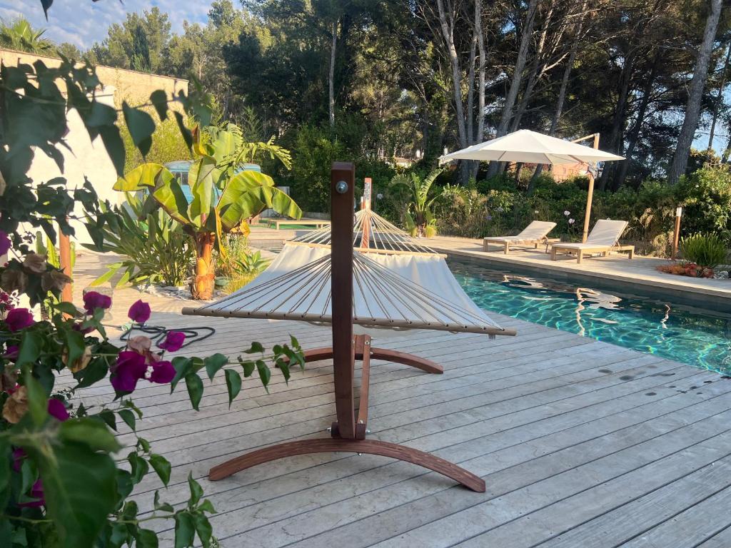 une terrasse en bois avec un hamac à côté d'une piscine dans l'établissement Pandora, à Sanary-sur-Mer