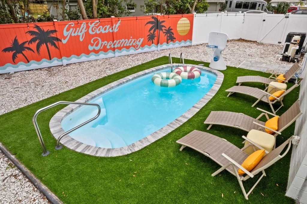 a swimming pool with chairs and a table at Resort Style Backyard Pool Sport Court Putt Putt in Seminole