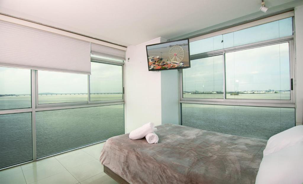 a bedroom with large windows and a bed with a television at Suite 7 Riverfront 1, Puerto Santa Ana, Guayaquil in Guayaquil