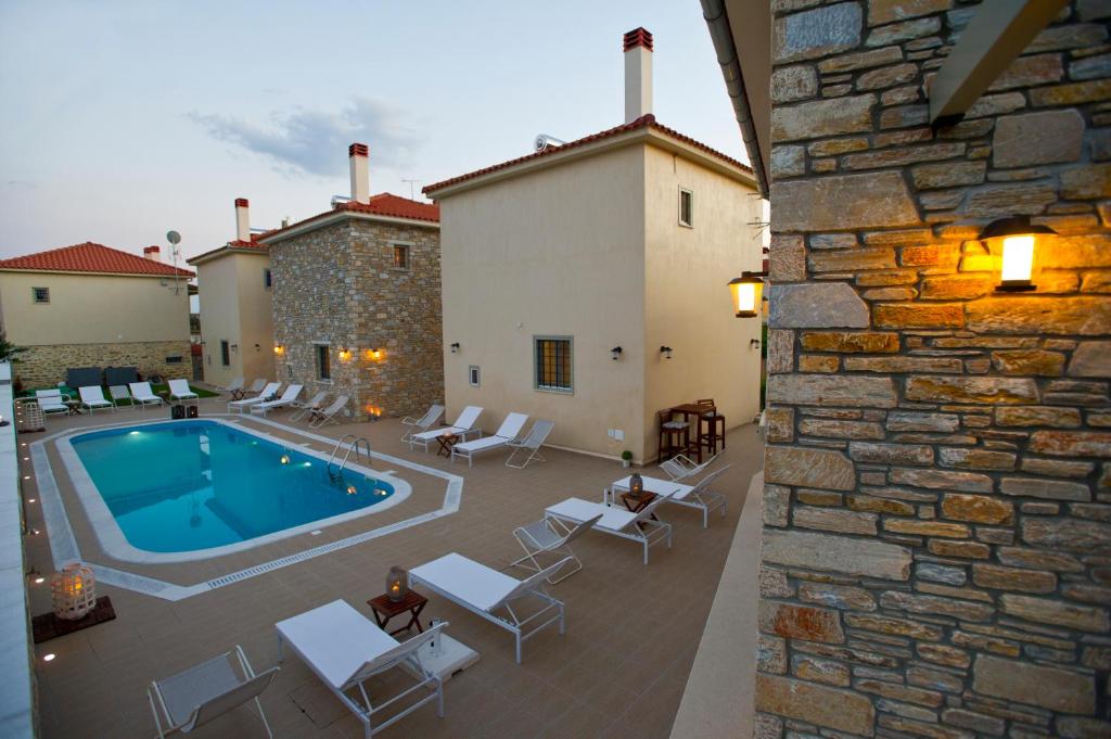 a patio with a pool and chairs and a building at Chroma Pelion Villas in Kato Gatzea