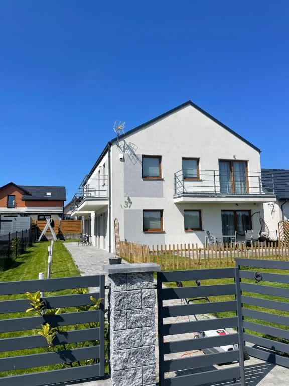 a white house with a fence in front of it at Apartamenty Paradise in Tupadła