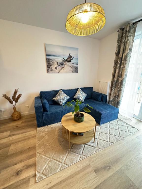 a living room with a blue couch and a table at Dune & Sea in Ustronie Morskie