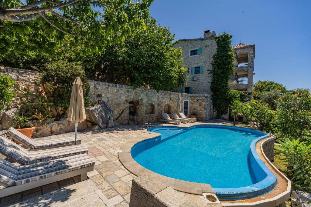 佩特罗瓦纳莫鲁Olive Resort & Villas的一座带遮阳伞的游泳池以及一座建筑