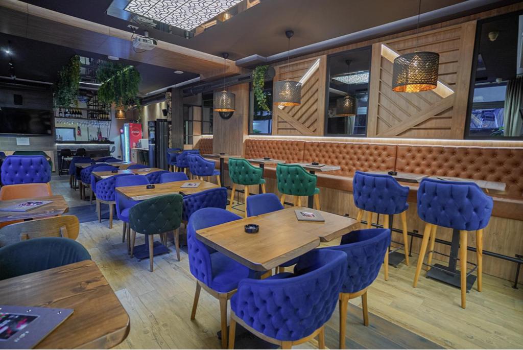 restauracja z drewnianymi stołami i niebieskimi krzesłami w obiekcie Terase Zlatibor apartmant 115 w mieście Zlatibor