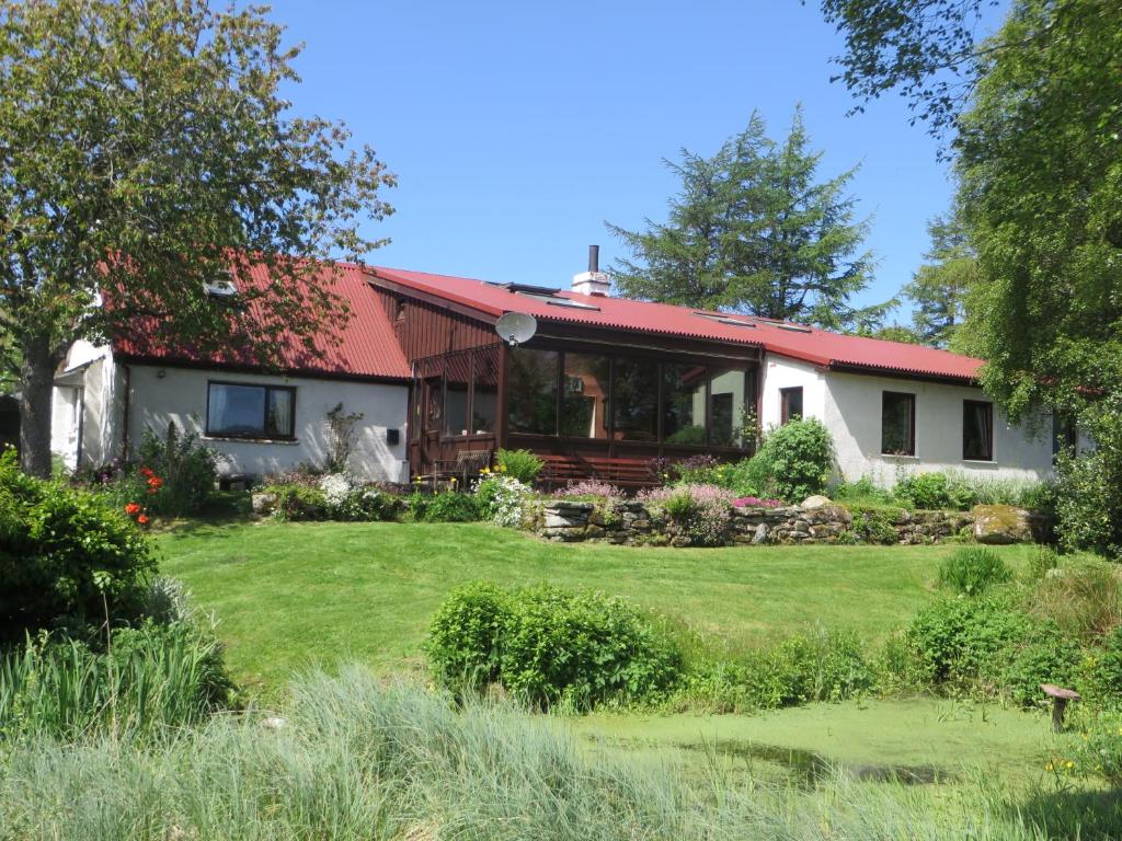 a house with a red roof and a yard at Invercassley Cottage B & B Suite in Lairg