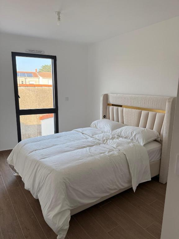 ein weißes Bett in einem Zimmer mit Fenster in der Unterkunft Maison La Pornicaise 11 in Saint-Jean-de-Monts