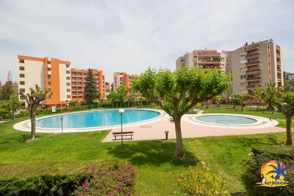 a swimming pool in a park with tall buildings at Cordoba IBERPLAYA in Salou