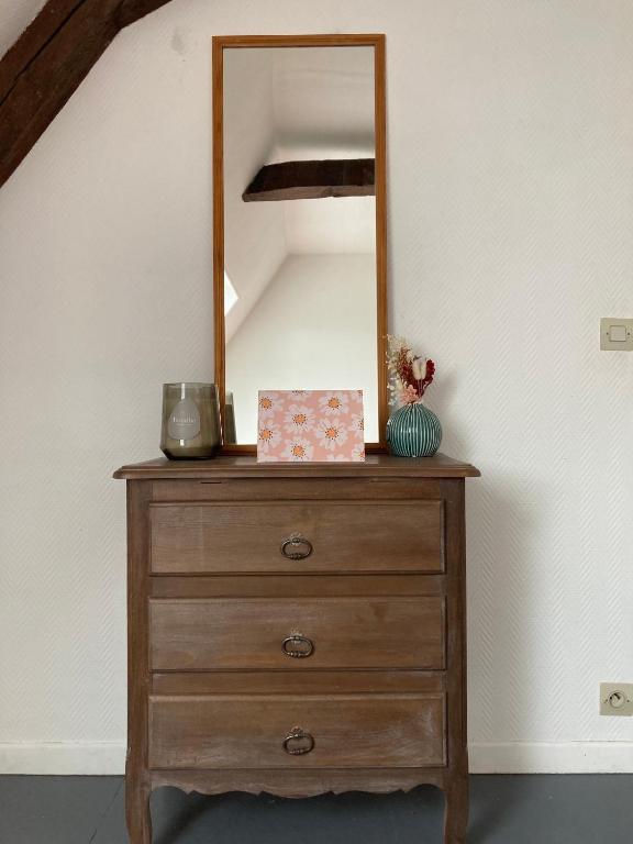 - une commode en bois avec un miroir au-dessus dans l'établissement Au pied du Logis Royal, à Loches