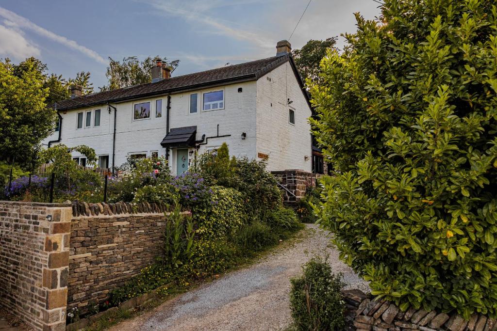 a white house with a brick wall at Wells Cottage in Holmfirth