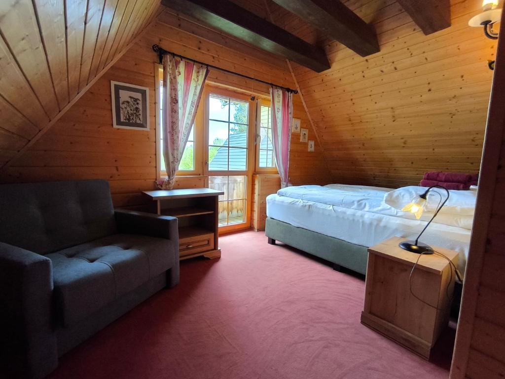 a bedroom with a bed and a couch and a window at Osada Magury - Bieszczady in Wetlina