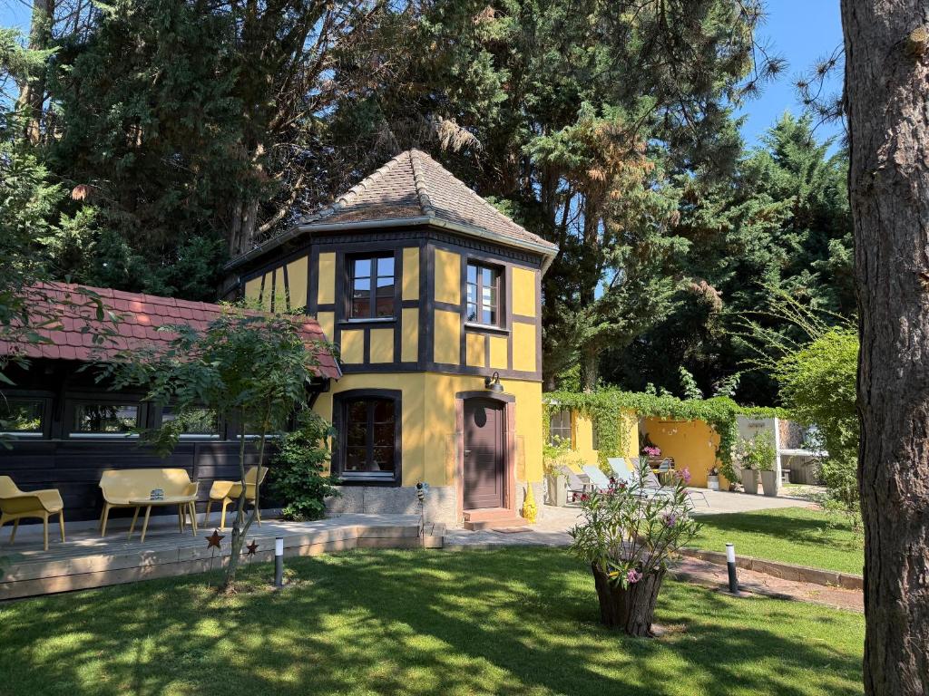 une maison jaune avec une table et des chaises dans une cour dans l'établissement Le Parc du Séquoia & SPA proche Colmar et Riquewihr, à Ostheim