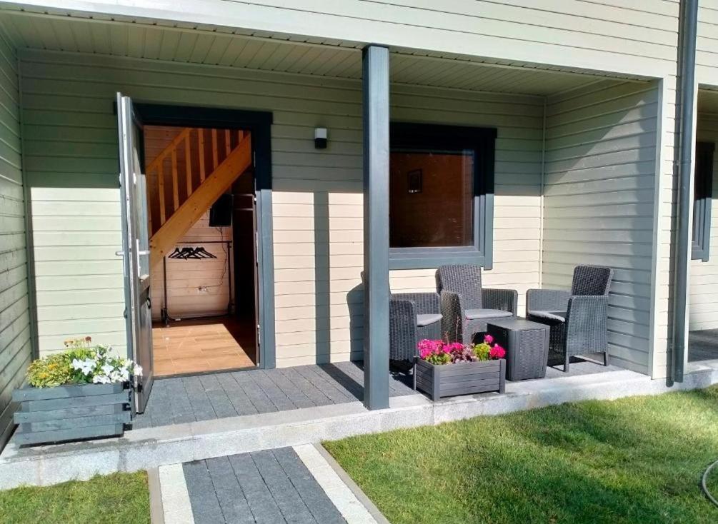 a house with a patio with chairs and flowers at Szare Domki in Mrzeżyno