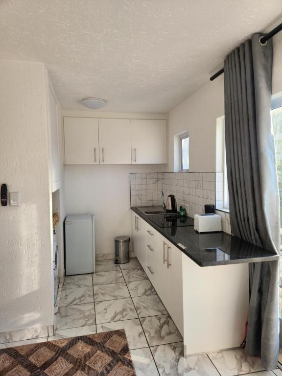 a kitchen with white cabinets and a black counter top at Hayley's inn at village blues in Johannesburg