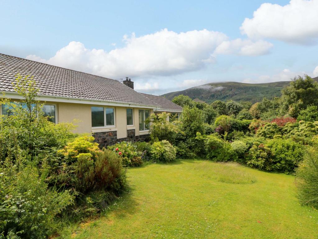 a house with a garden and mountains in the background at Knockendoch in Dumfries