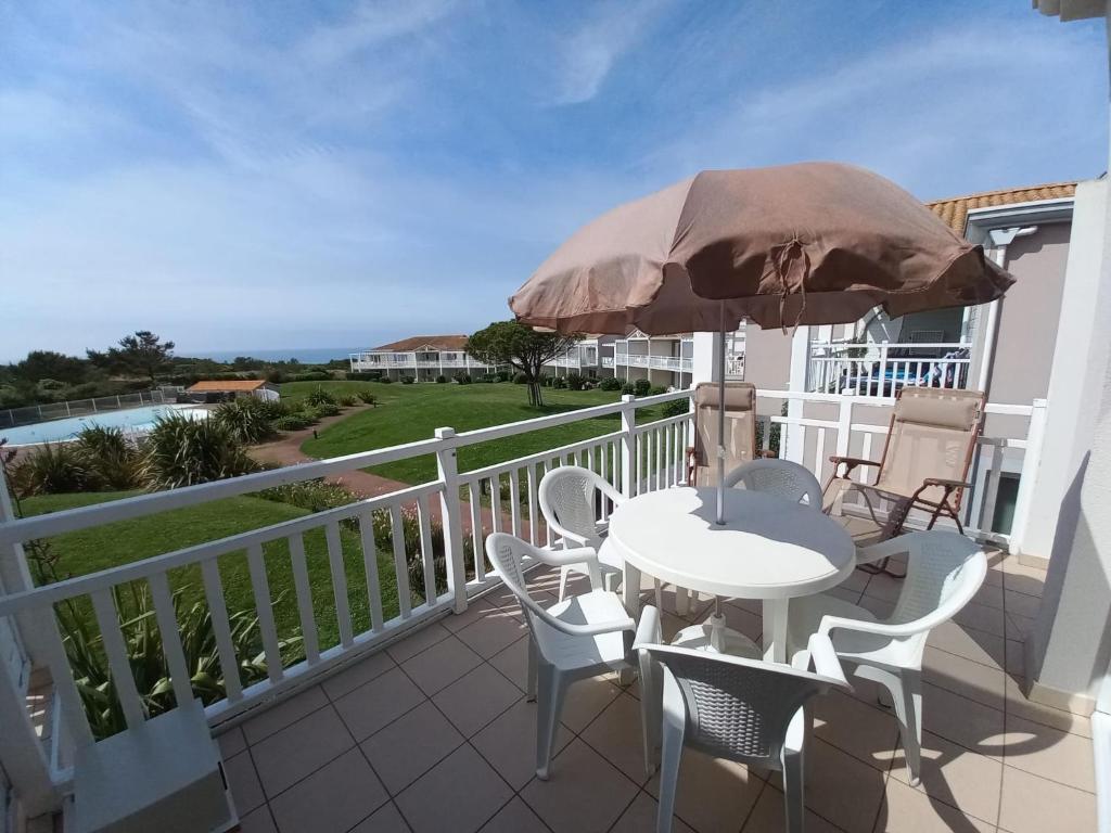 een balkon met een tafel en stoelen en een parasol bij Les Sables-d'Olonne - Vue Mer, Terrasse, Wifi Fibre & Piscine, à 2 pas de l'Océan - E101 in Les Sables-dʼOlonne