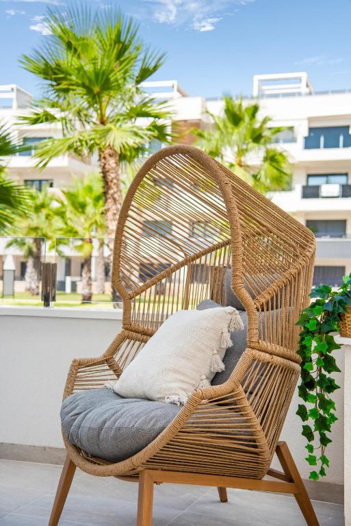 a wicker chair with pillows on a balcony with palm trees at Casa Azul in La Florida