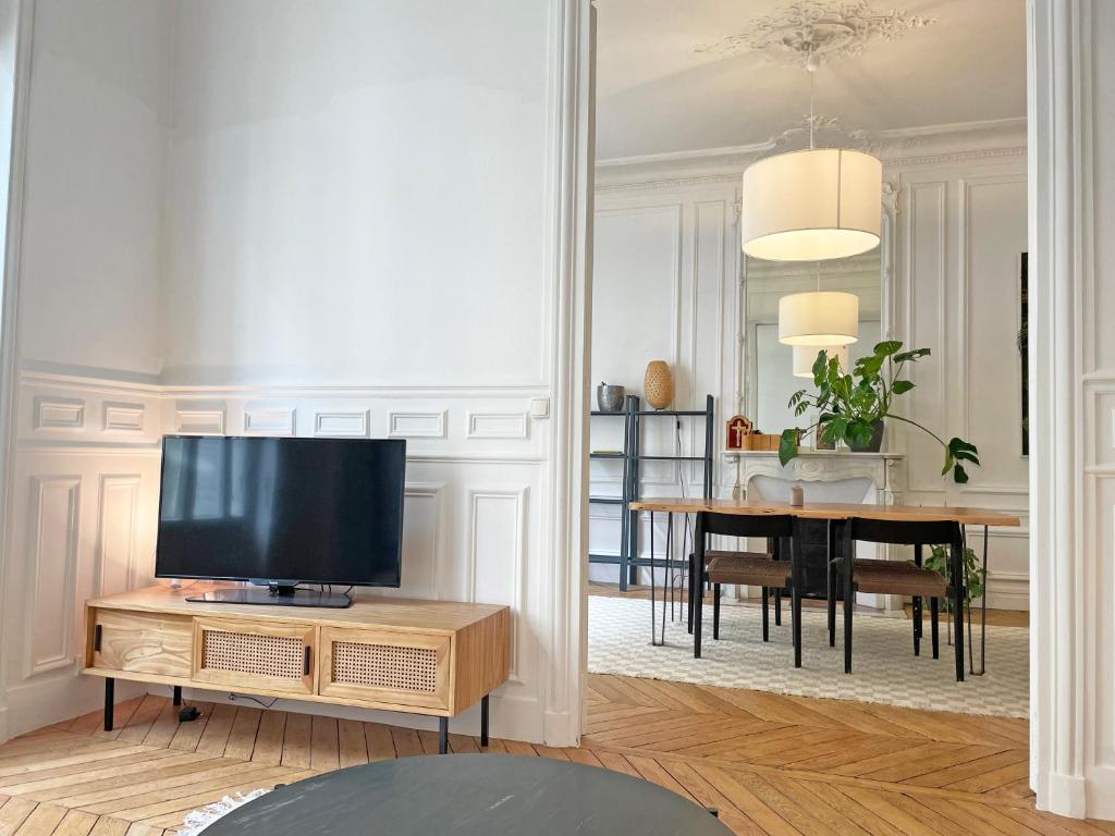 ein Wohnzimmer mit Fernseher und Tisch in der Unterkunft Magnific appartment near Arc de Triomphe in Paris
