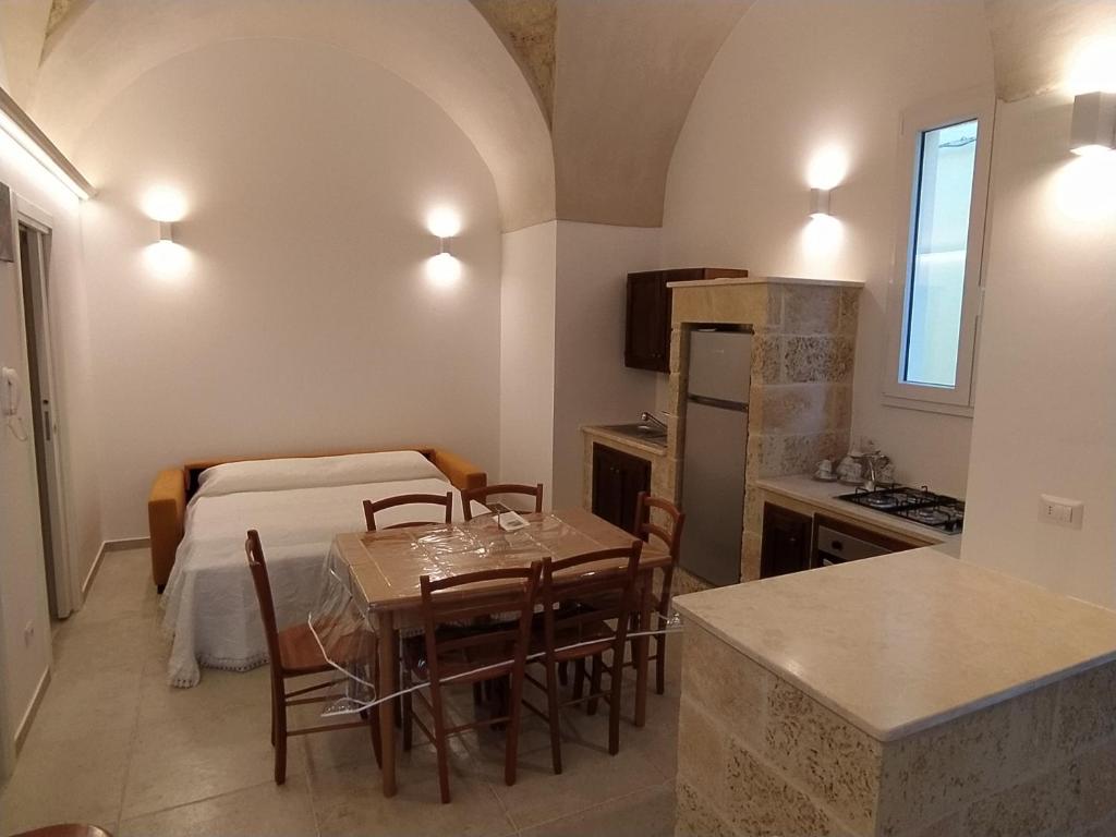 a kitchen and dining room with a table and a bed at Casa Vacanza Al Vicolo della Colonna nel centro storico di Presicce in Presicce