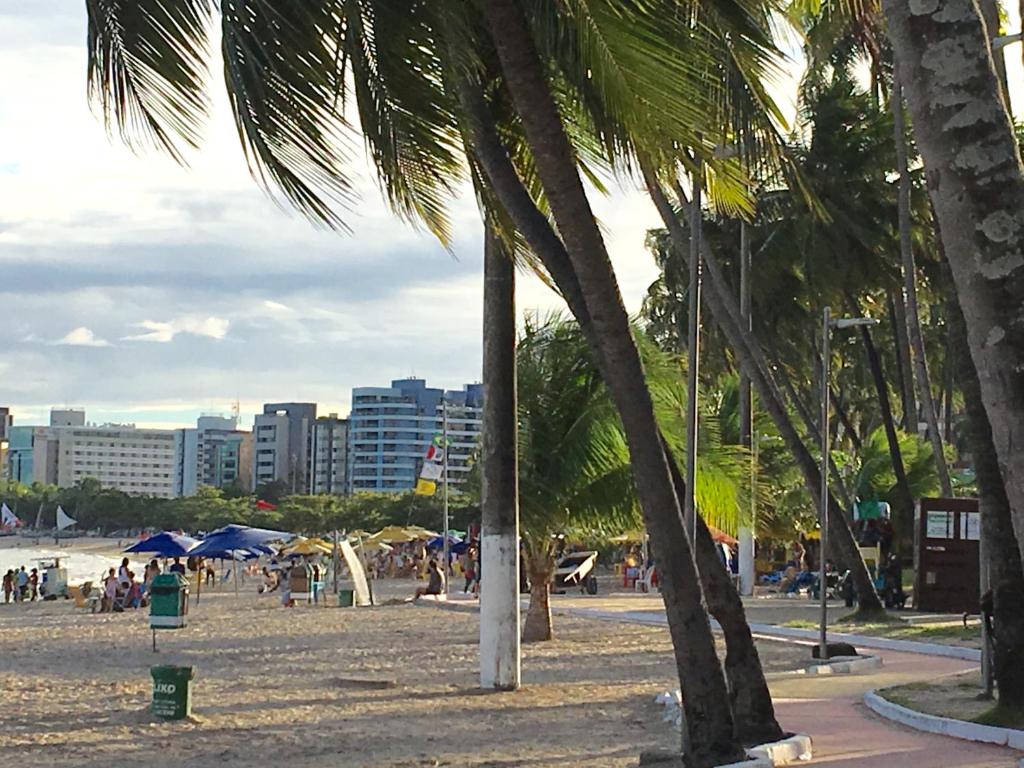 a group of people on a beach with palm trees at Apartamento Na Ponta Verde in Maceió