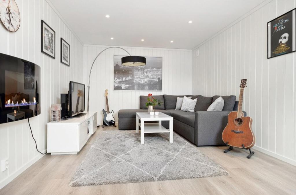 sala de estar con sofá y guitarra en Summer place by the river, en Drammen