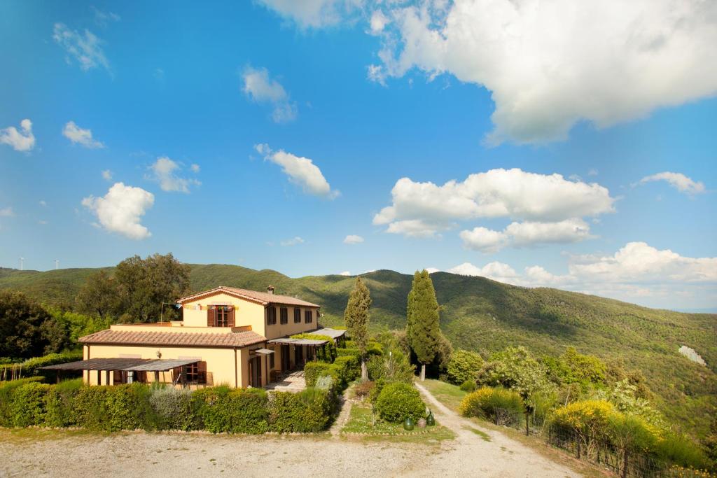 a house on a hill with a dirt road at Casale Pundarika in Riparbella