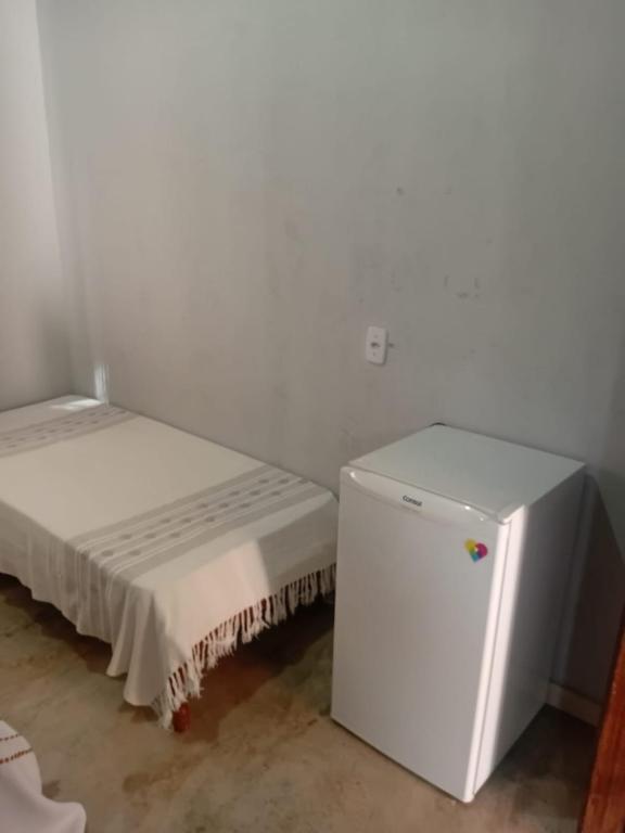 a white room with a small refrigerator and a bed at Suítes da Raquel Ype Amarelo in Alto Paraíso de Goiás