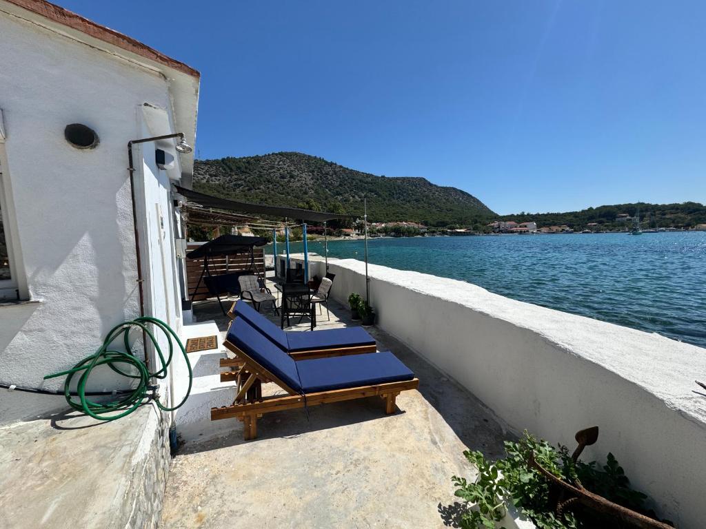 a group of blue chairs on a balcony next to the water at Riva Blue Silence -Seafront Retreat in Poseidónion
