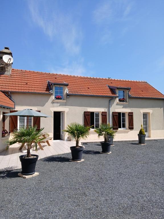 un bâtiment avec des plantes en pot devant dans l'établissement Gîte charmant à 35 minutes plages du débarquement, à Saint-Georges-dʼElle