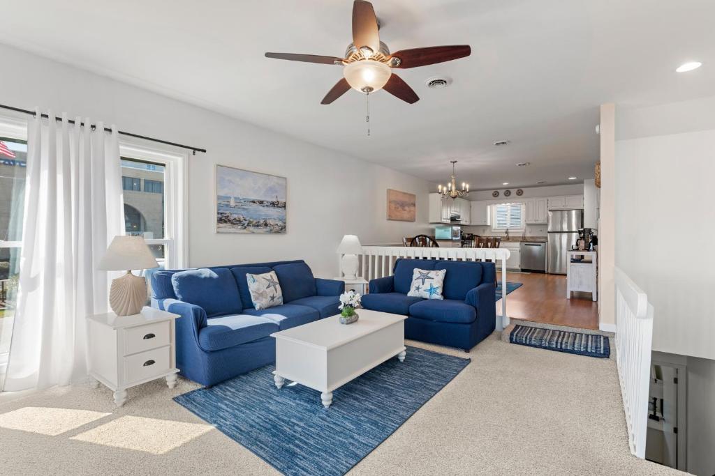 a living room with blue couches and a ceiling fan at Sea Escape in Kill Devil Hills