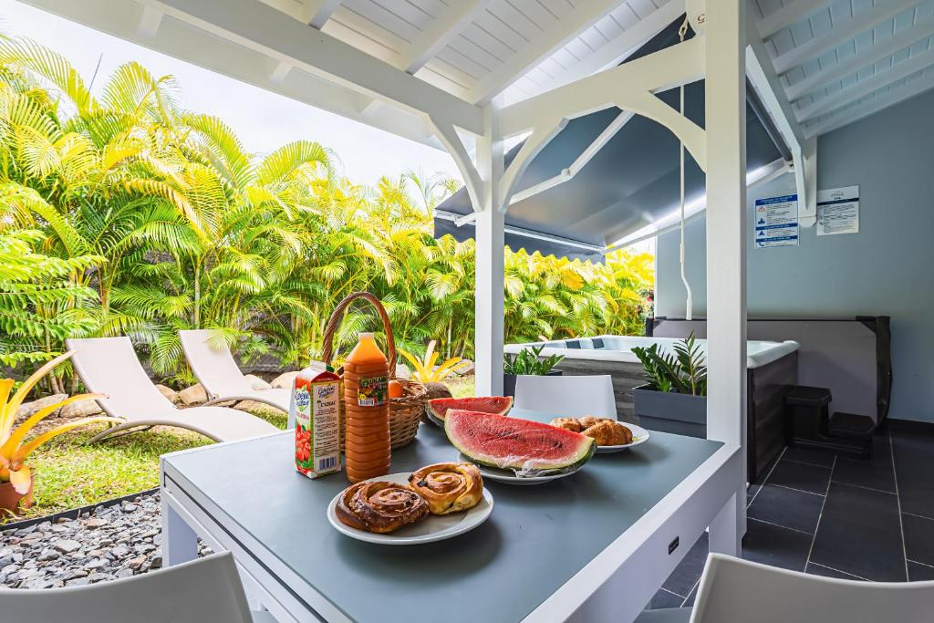 Una mesa con platos de comida en un patio. en Villa Alamanda à 1400 m de la mer - Jacuzzi privé, en Sainte-Anne