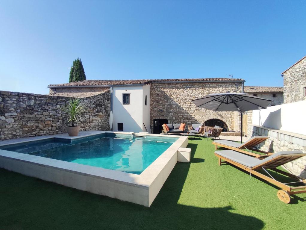 a swimming pool with two chairs and an umbrella at Charmante maison provençale proche d'Uzès in Garrigues-et-Sainte-Eulalie