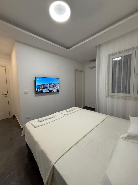 a bedroom with a large white bed with a tv on the wall at Skyline View Apartment in Ulcinj