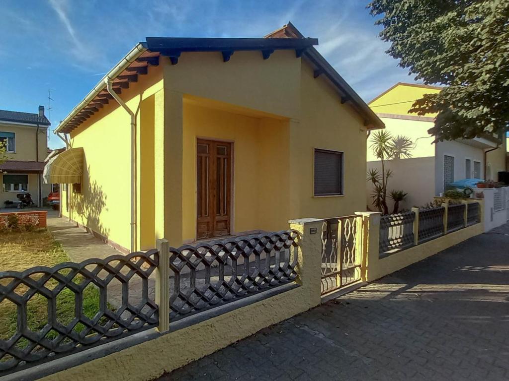a small yellow house with a fence in front of it at Villetta il Camuciolo in Torre del Lago Puccini