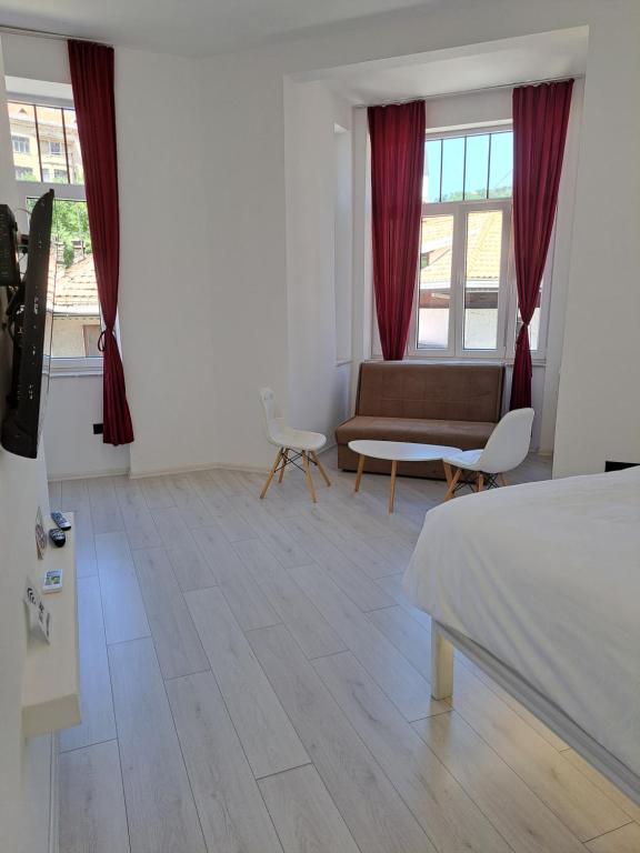 a bedroom with a bed and a couch and windows at NEW - Old Town Pearl Apartments in Sarajevo
