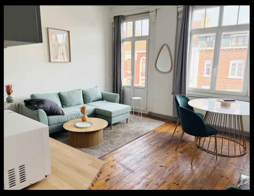 un salon avec un canapé bleu et une table dans l'établissement Perle de Liévin, à Liévin