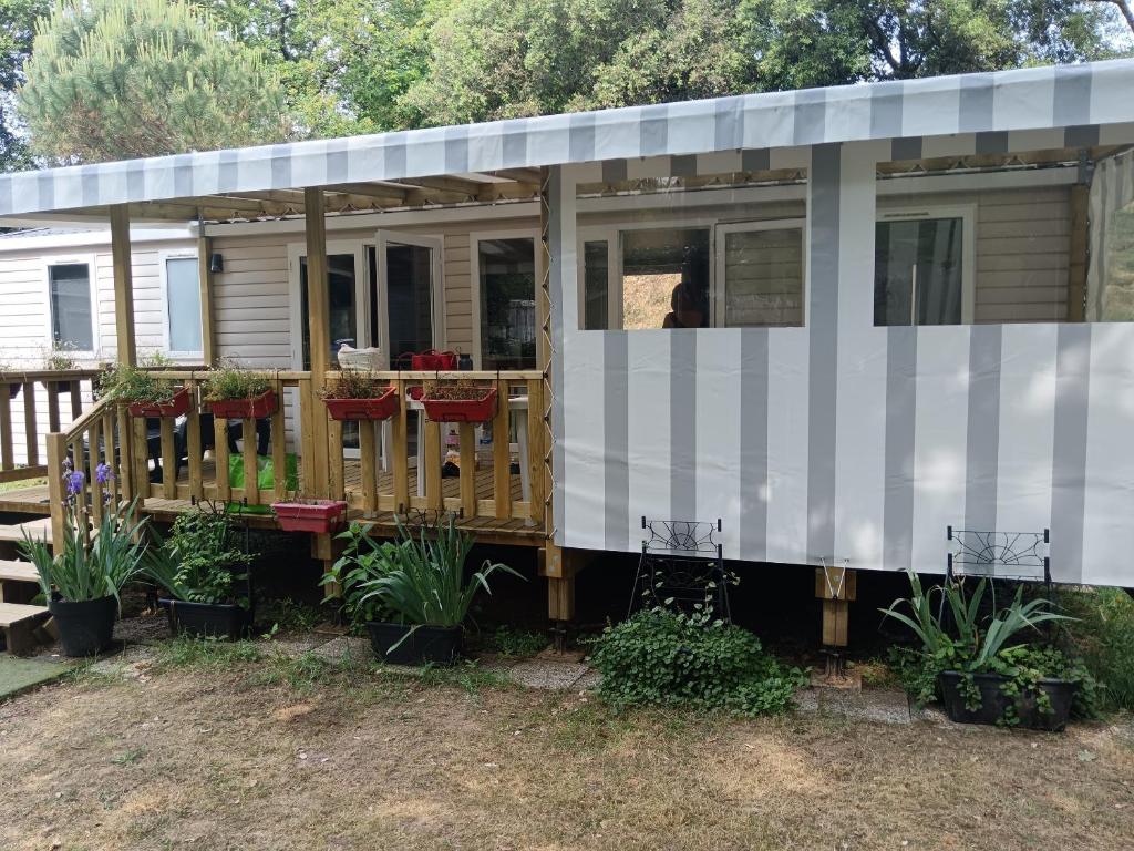 une petite maison avec un porche et une terrasse dans l'établissement Mobil-home 6-8 pl., à Saint-Brévin-les-Pins