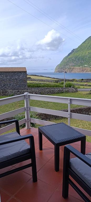 two benches sitting on top of a balcony overlooking the ocean at Chez Tronqueira 43 in Faja Grande