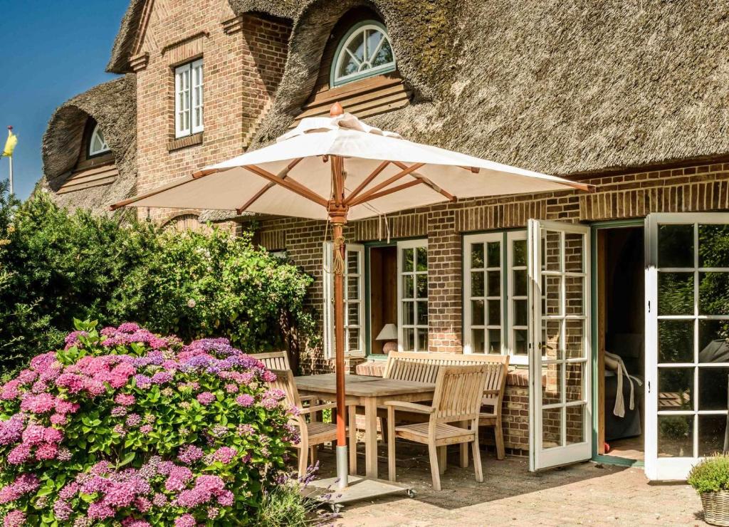a table with an umbrella in front of a house at Sylt Glück in Morsum
