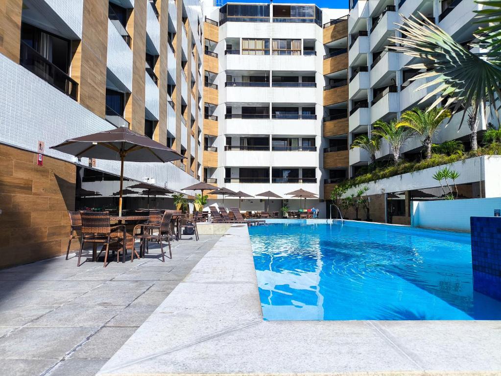 a swimming pool with chairs and umbrellas next to a building at Aptos super confortáveis no Gold Flat by Apartamentos Jampa in João Pessoa