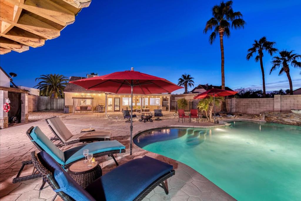 a swimming pool with chairs and an umbrella at Private Oasis With The Best Backyard! in Phoenix