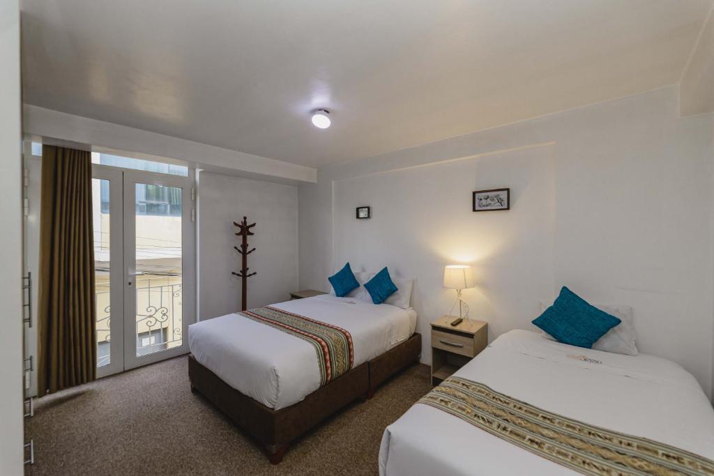 een slaapkamer met twee bedden en een balkon bij Cozy Room Cusco in Cuzco