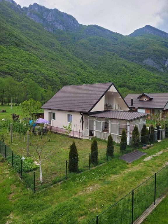 a house in a field with mountains in the background at Lola Guest House in Vusanje