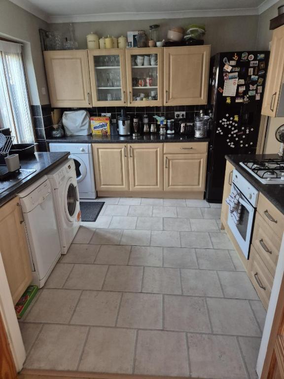 a kitchen with wooden cabinets and a tile floor at Rowell in Barking