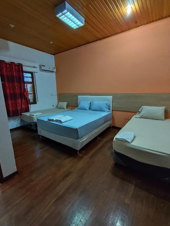 due letti in una stanza con pavimenti in legno di CEDE Inn Hotel a Encarnación
