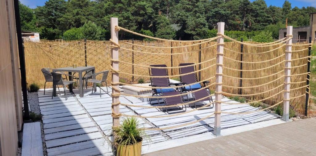 eine Terrasse mit Stühlen, einem Tisch und einem Zaun in der Unterkunft Apartament Szyszka 2 in Rogowo