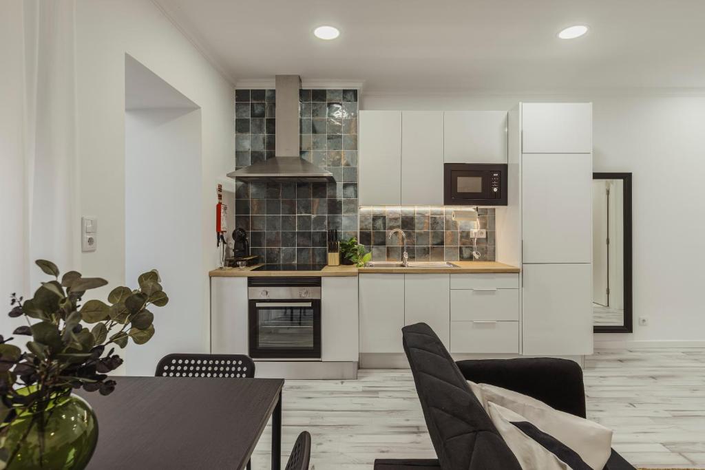 a kitchen with white cabinets and a table with chairs at Amadora Flat 3 in Amadora